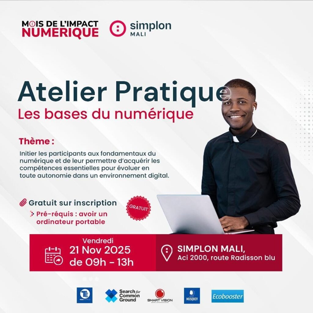 Jeune homme souriant en chemise noire, debout derrière un ordinateur portable.